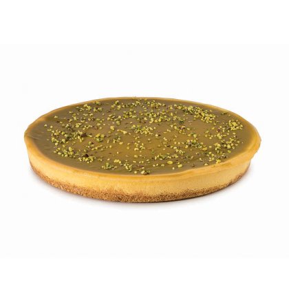 Okrugla torta s glatkom karamel glazurom, keksastom podlogom i posutim mrvicama pistacija.
