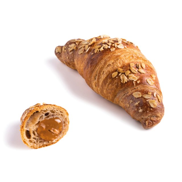 Zlatni kroasan sa zobi, manji prerezani komad otkriva karamel punjenje, na bijeloj pozadini